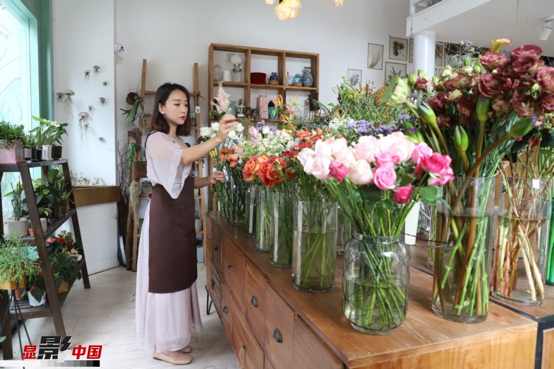 王黎媛是一名河南姑娘，在昆明念完大學后，就再也舍不下春城的藍天陽光、青山碧水，更舍不下這里的四時繁花，于是就干脆留了下來，成了一名媒體人。2017年的時候又毅然辭去工作，創(chuàng)業(yè)開起了花店，成了都市里的一名“花房姑娘”。圖為王黎媛在自己的花店中整理鮮花。新華網(wǎng) 周亞平/攝 念新洪/文